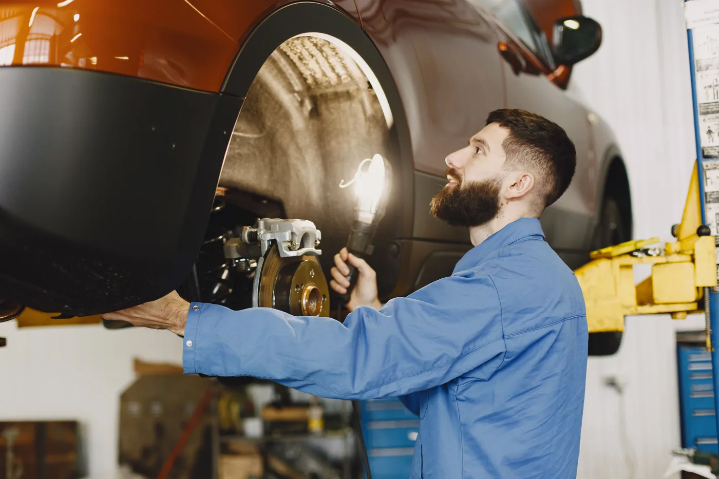 Mechaniker kontrolliert Bremskomponenten am hochgehobenen Fahrzeug