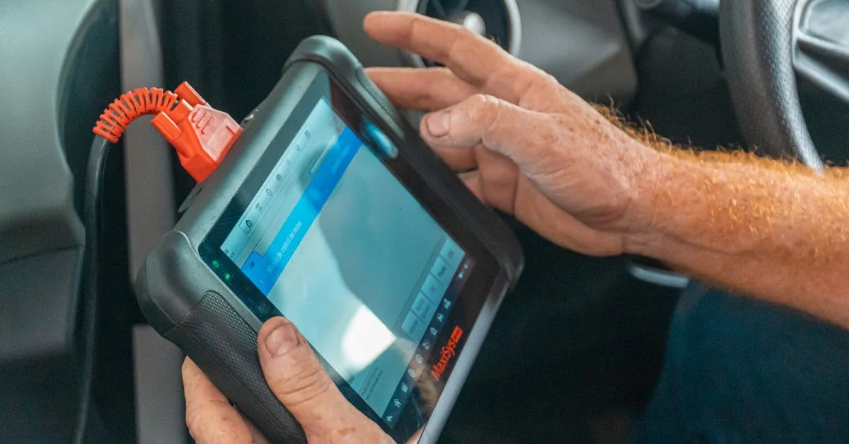 Hand bedient ein angeschlossenes Diagnosegerät im Fahrzeuginnenraum